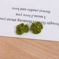 Makroaufnahme grüner handgehäkelter Blumen mit goldenem Ring und Perlenakzenten - Olivgrün