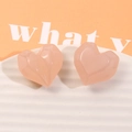 Dettaglio di ciondoli a cuore in resina rosa pesca con sfaccettature geometriche su vassoio - Rosa
