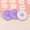 Dettaglio macro di bottoni rotondi in resina lavanda a quattro fori su un vassoio decorativo - Viola