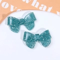 Detailed macro view of two glittering turquoise resin butterfly bows with silver sequins - Blue