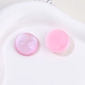 Dettaglio macro di cabochon tondi in resina rosa glitterata su piatto bianco per fai-da-te - Rosa Stile A