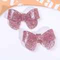 Macro shot of pink glitter bow hair clips with shimmering starry texture details - Pink