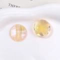 Close-up of Aurora iridescent multifaceted round yellow glitter charms on white ceramic - Orange