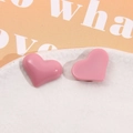 Macro shot of pink heart-shaped resin earrings on a marble stone jewelry display - Watermelon red
