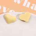 Close-up of heart-shaped cream yellow resin earrings with smooth glossy finish on ceramic - Yellow