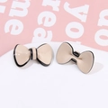 Dettaglio dell'accessorio a fiocco in acetato crema con bordo nero e clip in metallo - Champagne