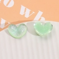 Close-up of mint green glitter resin heart cabochons for DIY hair accessories - Green