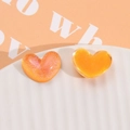 Macro detail of heart-shaped resin charms with shimmering glitter and aurora finish - Orange