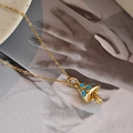 Artistic shot of a gold mushroom pendant necklace with blue enamel on a ceramic tray - Gold - Mushroom Necklace