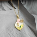 Dettaglio della collana con ciondolo floreale dorato con tulipano e farfalla - Pendaglio Fiore Farfalla / Rosa giallo