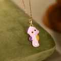 Vue macro d'un pendentif hippocampe rose mignon avec nageoires jaunes sur chaîne dorée - Collier Hippocampe Rose