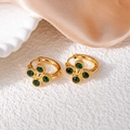 Dettaglio orecchini a fiore dorati con zirconi verdi su sfondo in pietra bianca - Stile Fiore a Quattro Petali Verde Scuro (1345)