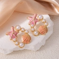 Détail de boucles d'oreilles étoile de mer dorées avec perles sur pierre blanche - Boucles d'Oreilles Créoles Étoile de Mer Orange (1499)