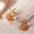 Gros plan de boucles d'oreilles étoile de mer et coquillage avec perles sur fond satin - Boucles d'Oreilles Clous Coquillage Étoile de Mer Orange (1505)