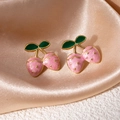 Gros plan de boucles d'oreilles fraises en émail rose sur du satin couleur champagne - Style Double Baie Rose (1518)