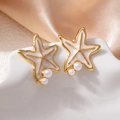 Gros plan de boucles d'oreilles étoile de mer dorées avec émail blanc et perles nacrées - Boucles d'Oreilles Clous Étoile de Mer Blanche Perle (1513)