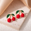 Dettaglio di orecchini a fragola rossi con foglie verdi e finitura dorata su pietra travertino - Stile Ciliegia Rossa con Foglia Verde (1539)
