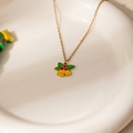 Detailopname van gouden kerstbelletjes hanger met hulstblaadjes en rode bessen - Groen Blad Bel Ketting