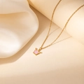 Detail van gouden ketting met roze kroonhanger op witte zijden stoffen achtergrond - Paars Kroon