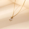 Détail d'un collier pendentif renne doré avec émail blanc et points marrons - Collier Cerf à Pois Blancs