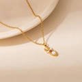 Detail view of a gold Christmas reindeer necklace with colorful enamel on a ceramic tray - Red Lips Reindeer Pendant Necklace