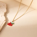 Minimalist stainless steel Christmas stocking pendant necklace on a warm stone background - Red Green Christmas Sock Necklace