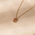 Macro detail of golden Christmas gift box pendant necklace with red bow and white dots - Christmas Gift Box Pendant Necklace