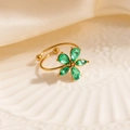 Detail of gold floral ring with five green teardrop stones on white ceramic plate - Green Five-Petal Flower (1674)