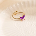 Elegant gold butterfly ring with purple zircon crystals on a textured ceramic surface - Purple Butterfly Style (1665)