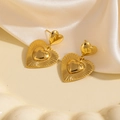 Détail macro de boucles d'oreilles cœur dorées superposées sur plat en céramique et soie - Pendentif Cœur Rayonné (1757)