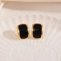 Détail de boucles d'oreilles dorées avec émail noir élégant sur un plateau de nacre - Pierre Noire Géométrique Clou (1849)