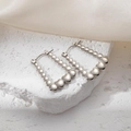 Pair of silver beaded U-shaped earrings with heart charm on white textured stone surface - Square Multi-Heart Earrings 0205