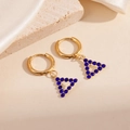 Details goldener Dreieck Ohrringe mit blauen Zirkonia auf weißem Satin-Hintergrund - Hohldreieck Blaue Zirkonia Ohrringe