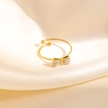 Détail macro d'une bague nœud dorée avec zircons brillants sur tissu satiné - Style Nœud Blanc