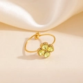 Gros plan d'une bague trèfle dorée avec zircons verts en forme de cœur sur soie - Style Trèfle Jaune