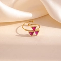 Gros plan de la bague dorée ajustable avec cristaux roses sur fond en satin élégant - Style Triangulaire Rouge