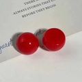 Primo piano di orecchini a bottone tondi in resina rossa su carta stile vintage - Stile Tondo Rosso