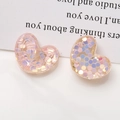 Makroaufnahme von herzförmigen Harzanhängern mit bunten Pailletten für DIY-Schmuck - Hellrosa