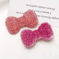 Close-up of glitter bow-shaped resin charms in dark rose and light pink for DIY crafts - Rose Red
