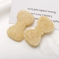 Close-up of bow-shaped DIY resin charms with sparkling sequins and crushed ice texture - Beige