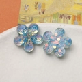 Close-up of colorful resin five-petal flower charms with iridescent glitter in a ceramic dish - Light Blue Flower