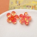 Macro shot of two translucent red resin flower charms with colorful laser sequins - Orange Flower