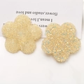Makroaufnahme von zwei gelben Harzblumen mit Glitzer-Matt-Textur für DIY-Schmuck - Beige