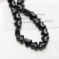 Close-up of glossy black heart-shaped ceramic beads for DIY jewelry making and crafts - Black