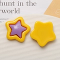 Detailed view of colorful star resin charms on a white plate for DIY jewelry making - Yellow + Purple