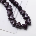 Macro shot of dark purple heart-shaped ceramic beads with marble texture and side holes - Deep purple