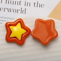 Macro detail of star-shaped resin charms in orange and yellow for DIY jewelry crafts - Orange + Yellow