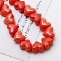 Macro shot of glossy red heart-shaped ceramic beads with unique marbled texture for DIY jewelry - Orange