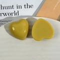 Dettaglio di accessori a cuore in resina giallo senape e verde oliva su piatto bianco - Stile Cuore Giallo
