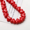 Close-up of glossy red heart ceramic beads for DIY jewelry making and crafting - Red